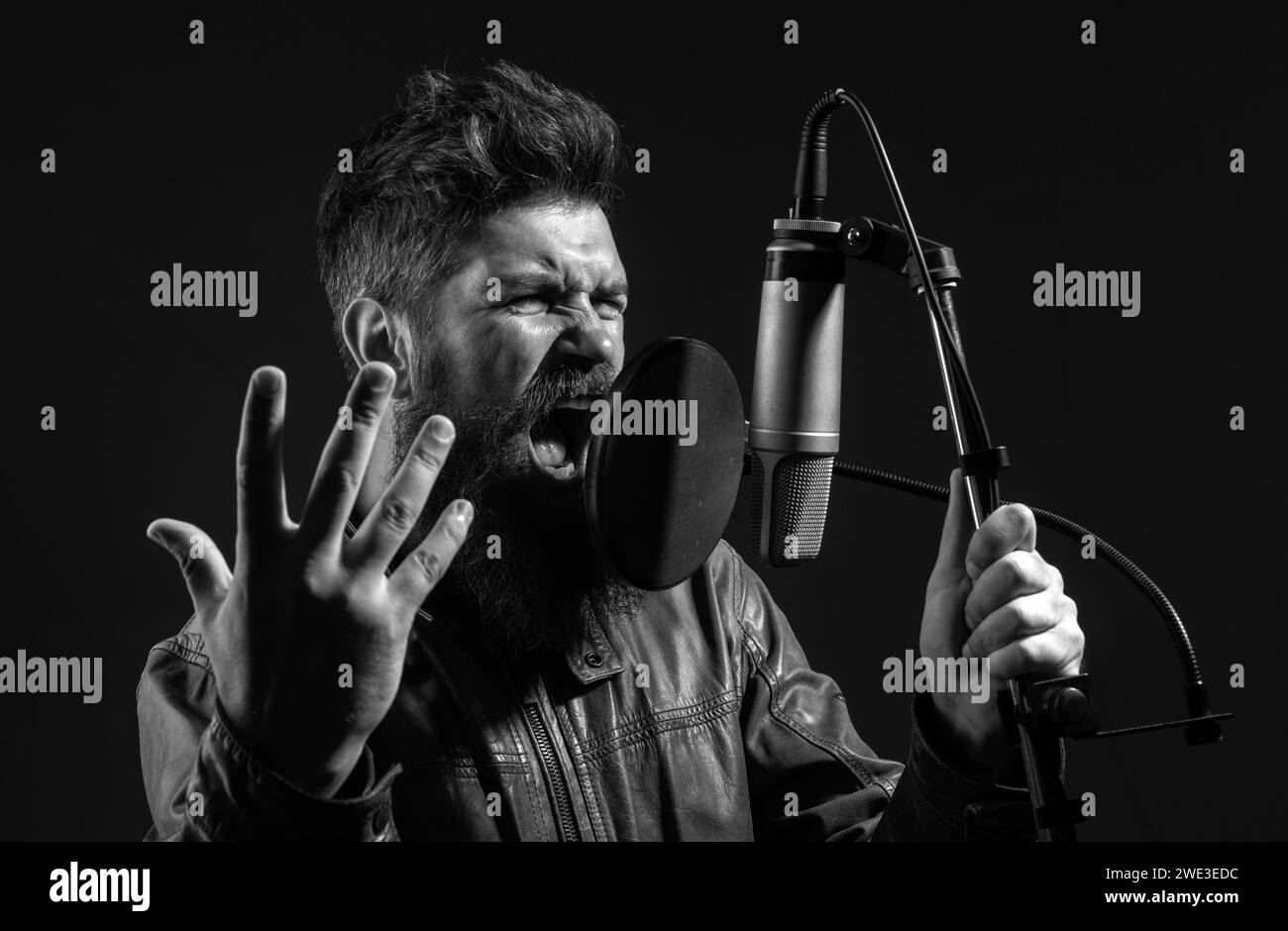 Bell'uomo in studio di registrazione. Musica esecuzione vocale. Cantante canto canzone con un microfono. Foto Stock