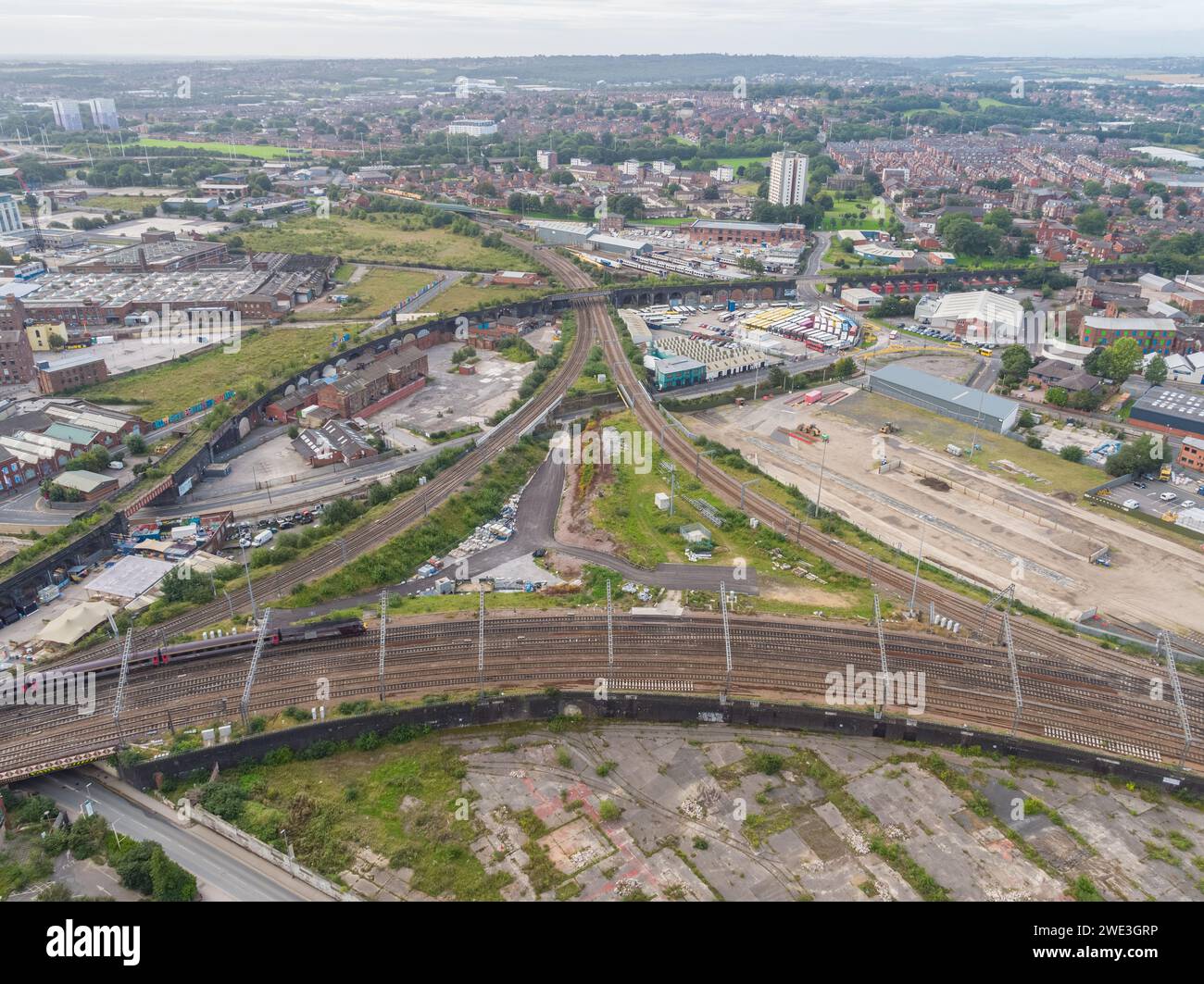 Fotografia aerea di un treno sulla linea principale dentro / fuori dalla stazione di Leeds con diramazioni che si dirigono verso ovest, e un viadotto e un ponte in disuso Foto Stock