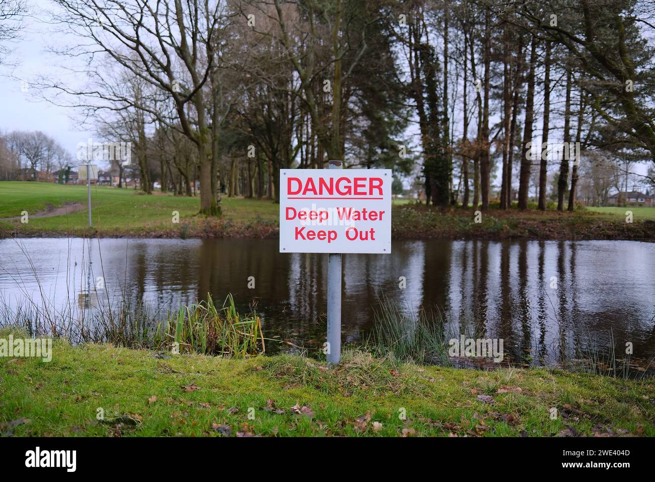 pericolo: segnale di pericolo acqua profonda in un laghetto pieno d'acqua rischio per il pubblico di annegamento Foto Stock