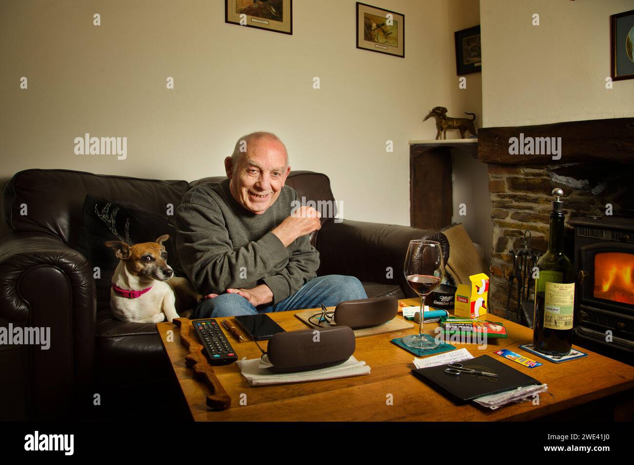 Vecchio seduto nel suo soggiorno con il suo cane da compagnia Foto Stock