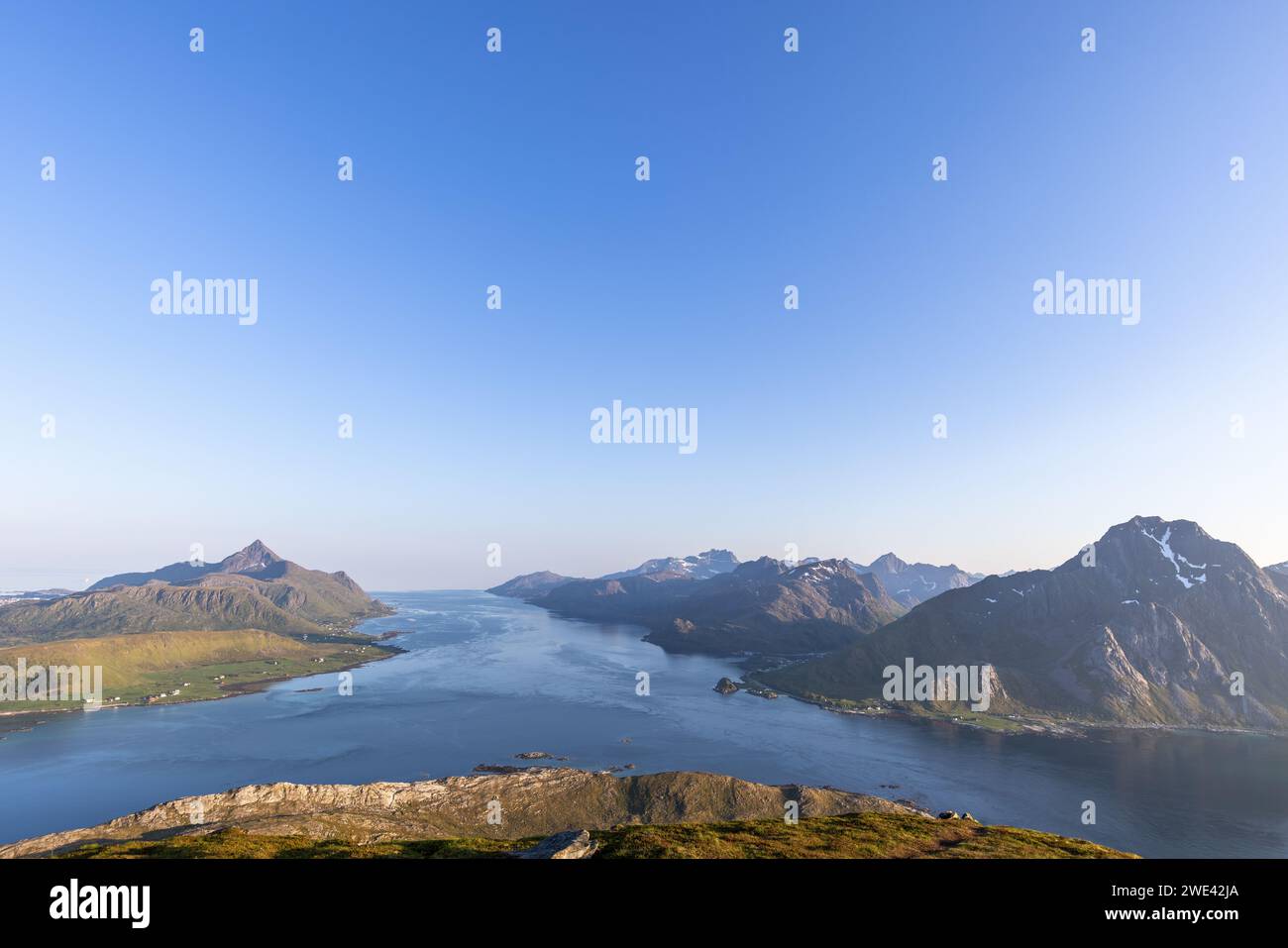 L'ora d'oro illumina il tranquillo paesaggio del fiordo di Nappstraumen, incorniciato dalle spettacolari vette dell'Offersoykammen nell'arcipelago delle Lofoten Foto Stock