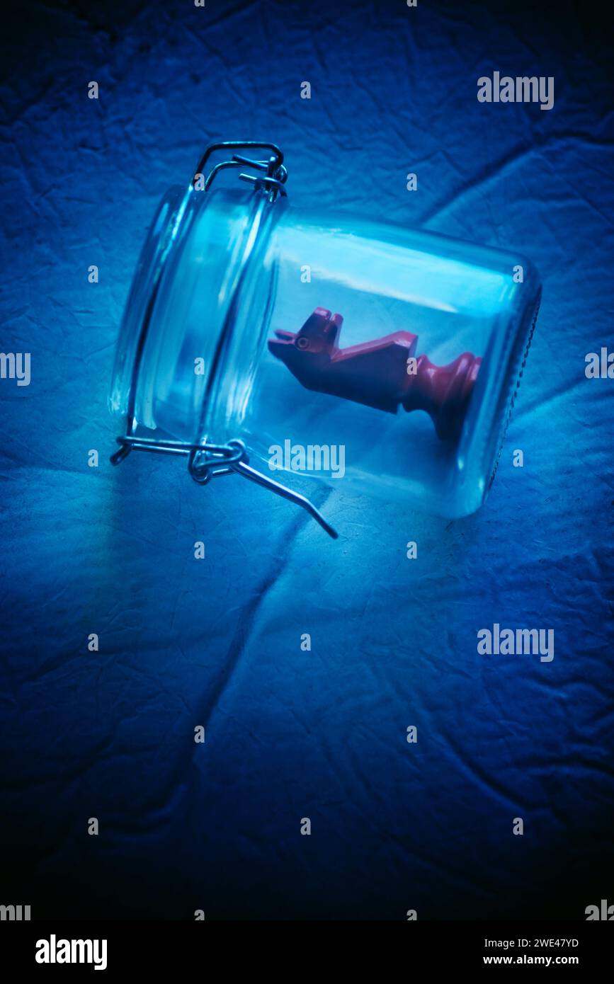 Pezzo rosso del cavaliere degli scacchi all'interno del vaso di vetro Foto Stock