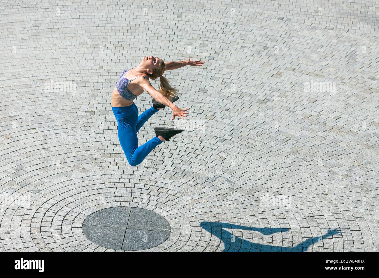 giovane donna in forma e muscolosa che salta in alto Foto Stock