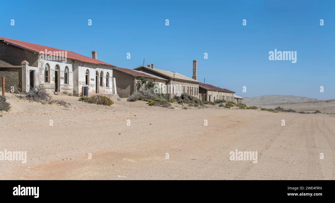 Paesaggio urbano con edifici di servizio abbandonati sulla sabbia nella città fantasma mineraria nel deserto, sparati in tarda primavera a Kolmanskop, Namibia, Africa Foto Stock