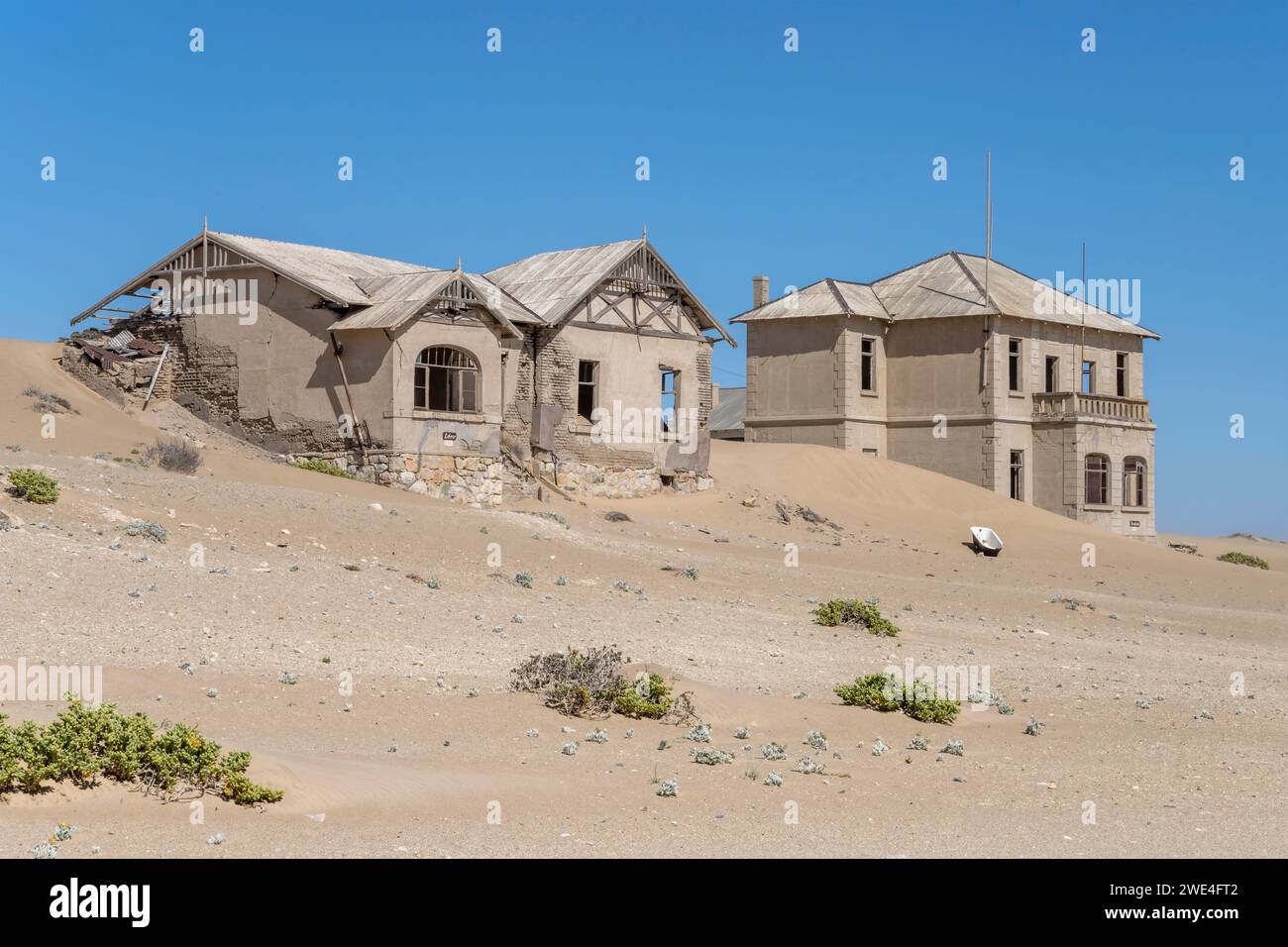 Paesaggio urbano con edifici abbandonati di "insegnante" e "architetto" sulla sabbia nella città fantasma mineraria nel deserto, sparati alla luce brillante di tarda primavera a Kolman Foto Stock