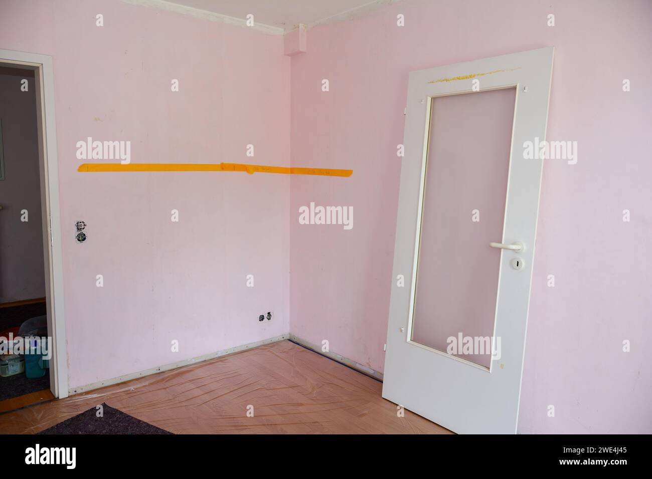 Pareti rosa con soffitto di un appartamento durante i lavori di ristrutturazione, porte sospese si aprono sulla parete Foto Stock