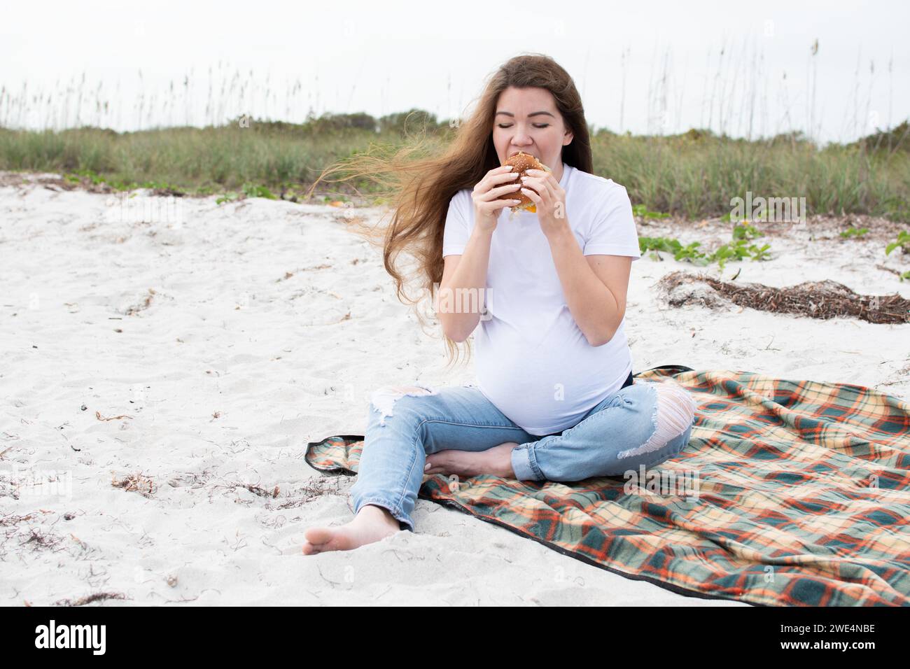 Donna incinta che mangia hamburger all'aperto. Mangiare durante la gravidanza. Concetto di dieta. Mangiare sano per la gravidanza Foto Stock