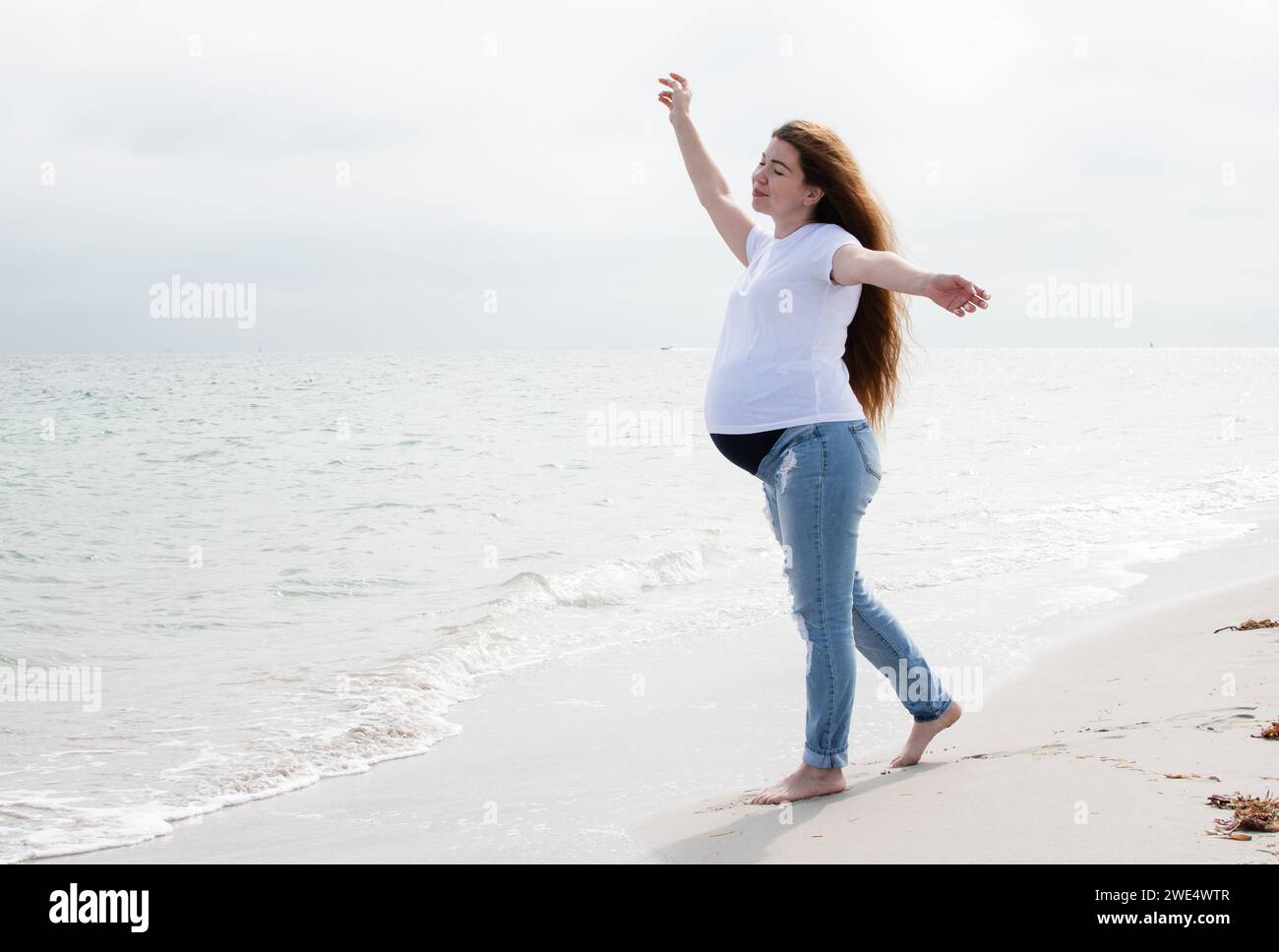 Donna incinta che si sta godendo l'oceano. Donna incinta sulla spiaggia. Felice gravidanza sana. concetto di benessere Foto Stock