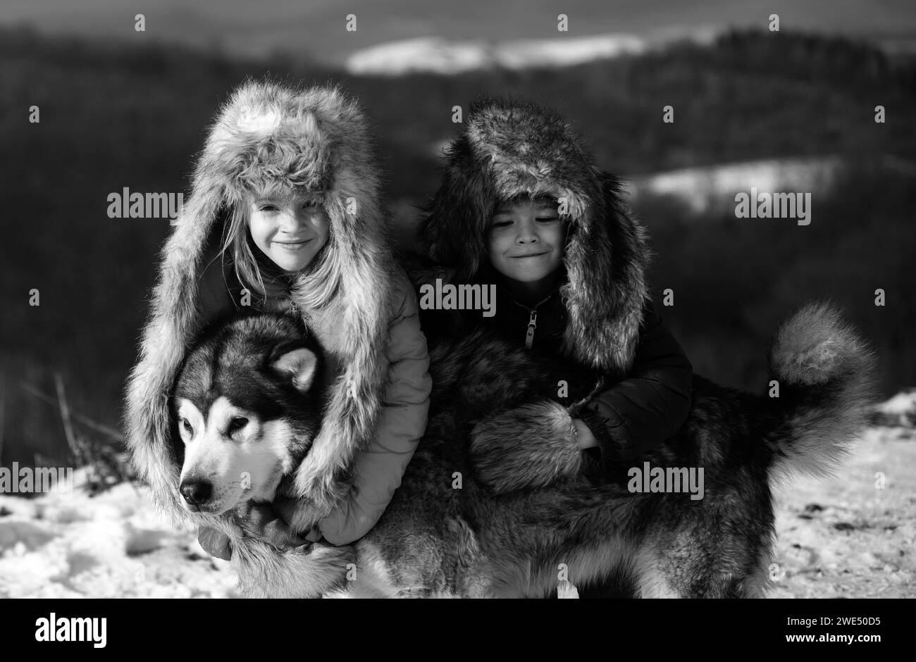 I bambini piccoli divertenti hanno abbracciato il cane Husky in inverno all'aperto. Sorridenti bambini amici abbracciare cane in gelo nevoso giorno all'aperto. Due bei ragazzi una ragazza che riposa Foto Stock