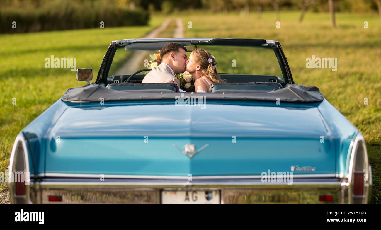 Foto divertenti, insolite, eleganti e originali con inversione di ruolo di una giovane e attraente coppia di nozze con bellissime auto veterane nella natura. Foto Stock