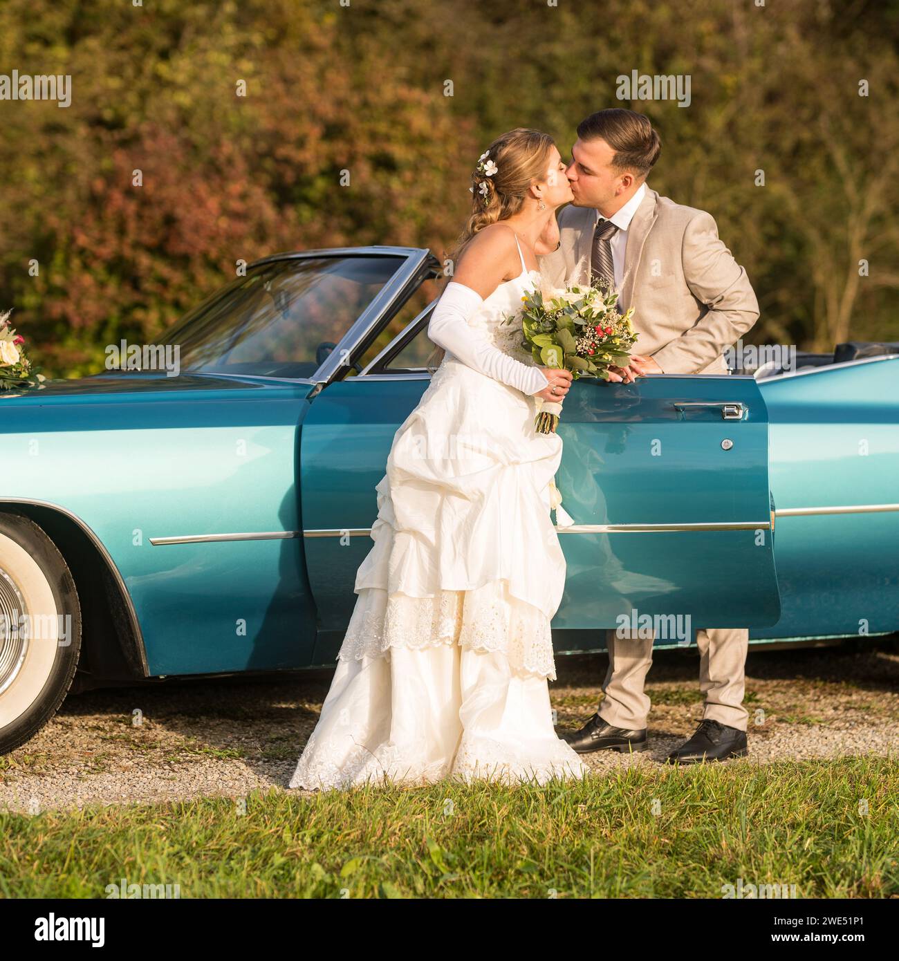 Foto divertenti, insolite, eleganti e originali con inversione di ruolo di una giovane e attraente coppia di nozze con bellissime auto veterane nella natura. Foto Stock