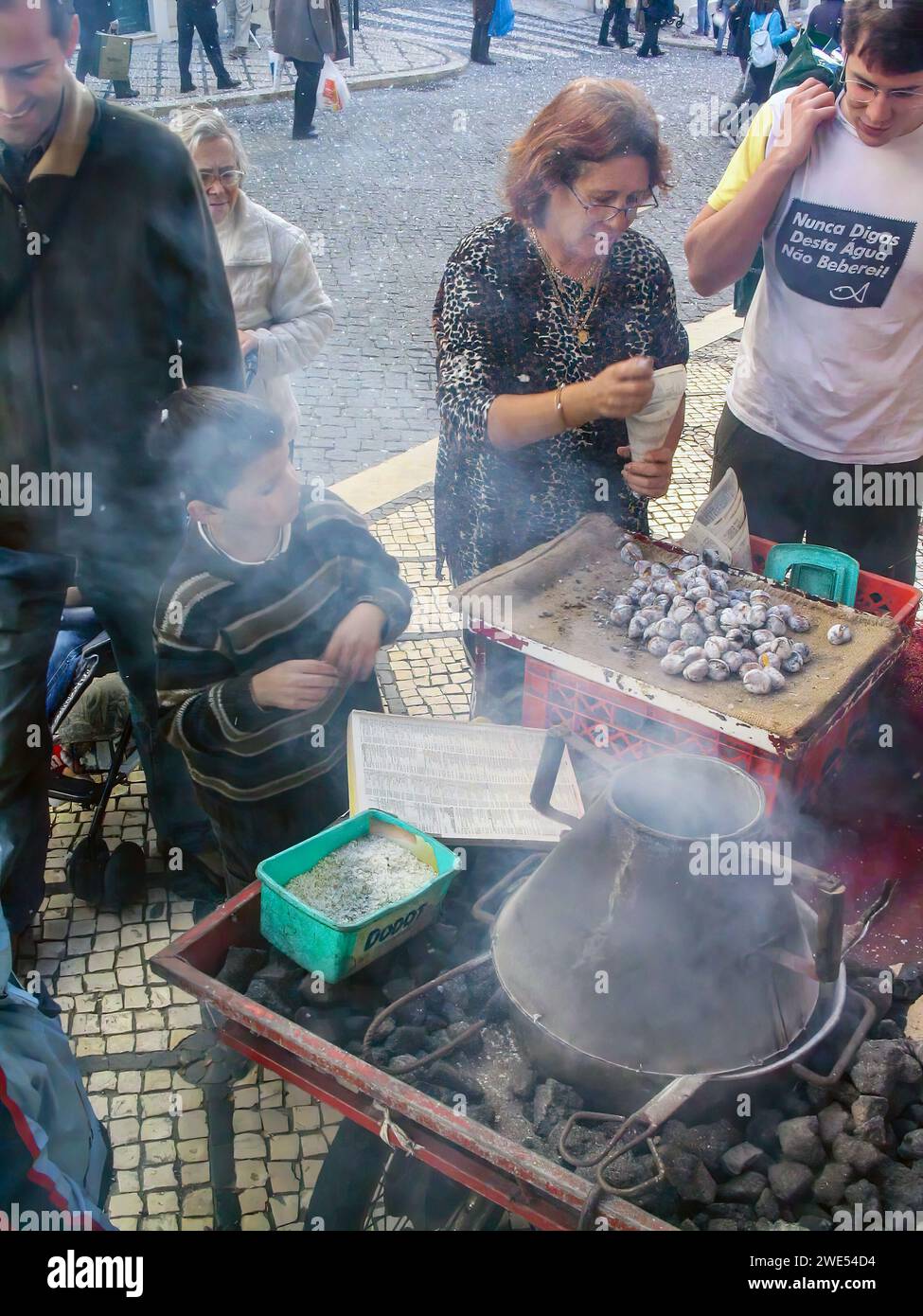 Lisbona, Portogallo: 10 novembre 2023: Venditore tradizionale di Castanhas Assadas o castagne arrosto e clienti felici. Tradizionale st Foto Stock