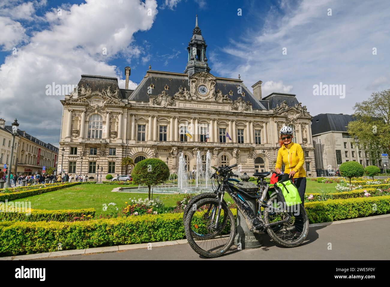 Donna in bicicletta sulla pista ciclabile della Loira, di fronte a fontane e giardini con municipio di Tours, Tours, Valle della Loira, sito patrimonio dell'umanità dell'UNESCO Foto Stock
