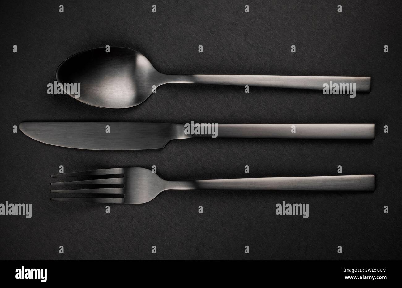 Set argenteria nera. Forchetta, coltello e cucchiaio su sfondo nero Foto Stock