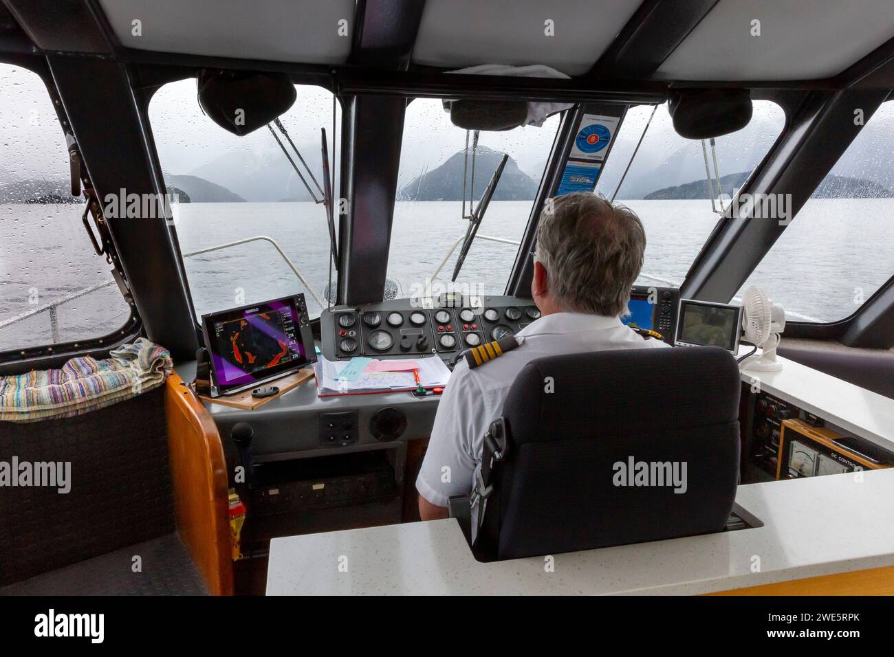 Capitano della nave che guida un traghetto passeggeri in catamarano Realnz sul lago Manapouri, Aotearoa (nuova Zelanda), te Waipounamu (Isola del Sud) Foto Stock