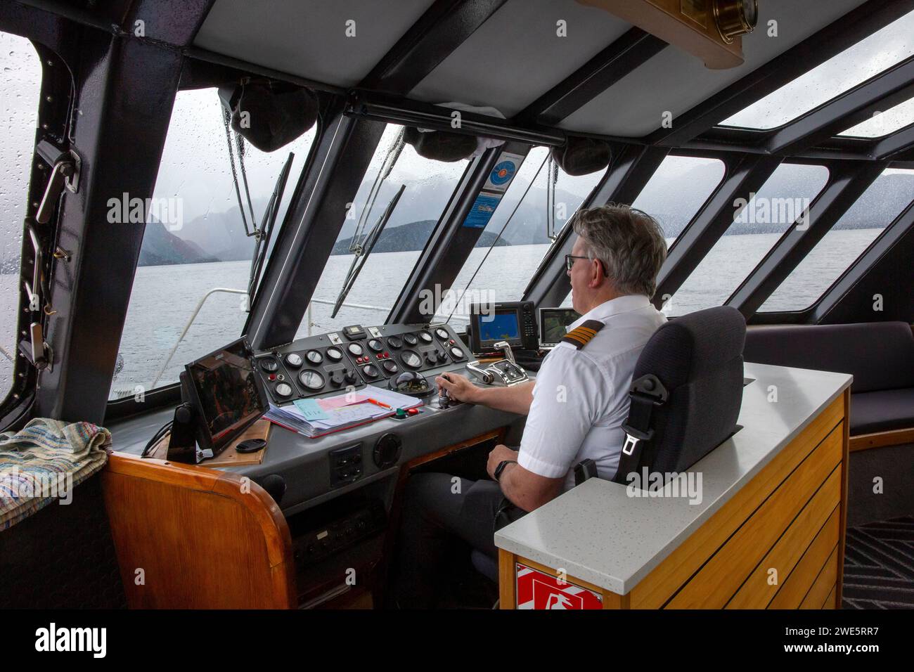 Capitano della nave che guida un traghetto passeggeri in catamarano Realnz sul lago Manapouri, Aotearoa (nuova Zelanda), te Waipounamu (Isola del Sud) Foto Stock