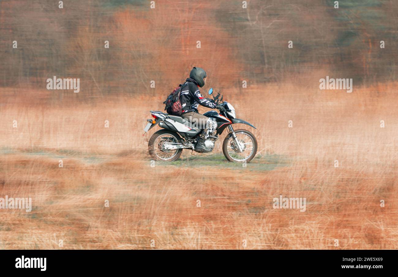 Un motociclista su una moto da fondo in campo. Foto Stock