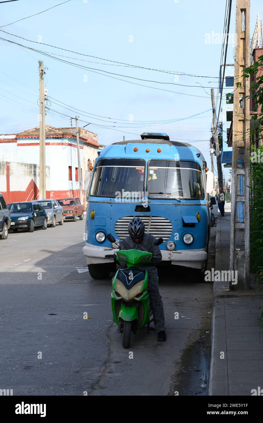 Un uomo in bicicletta elettrica è parcheggiato di fronte a un autobus obsoleto d'epoca in Maceo Street Foto Stock