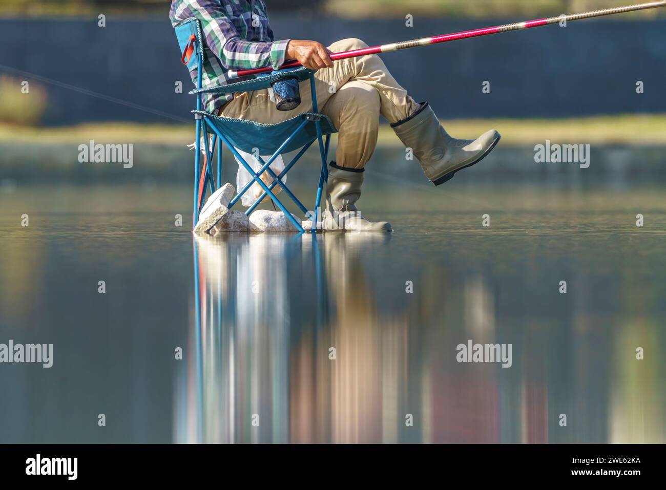 La sedia di un pescatore in riva al mare. Sedia da campeggio e canna da pesca Foto Stock