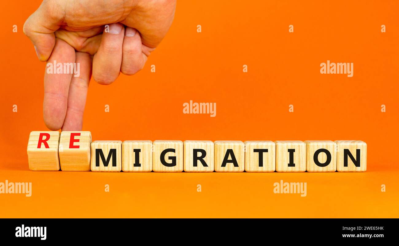 Simbolo di migrazione o di remigrazione. Concetto di Migration Remigration su bellissimi cubi di legno. Splendido sfondo arancione. Mano d'affari. Affari Foto Stock