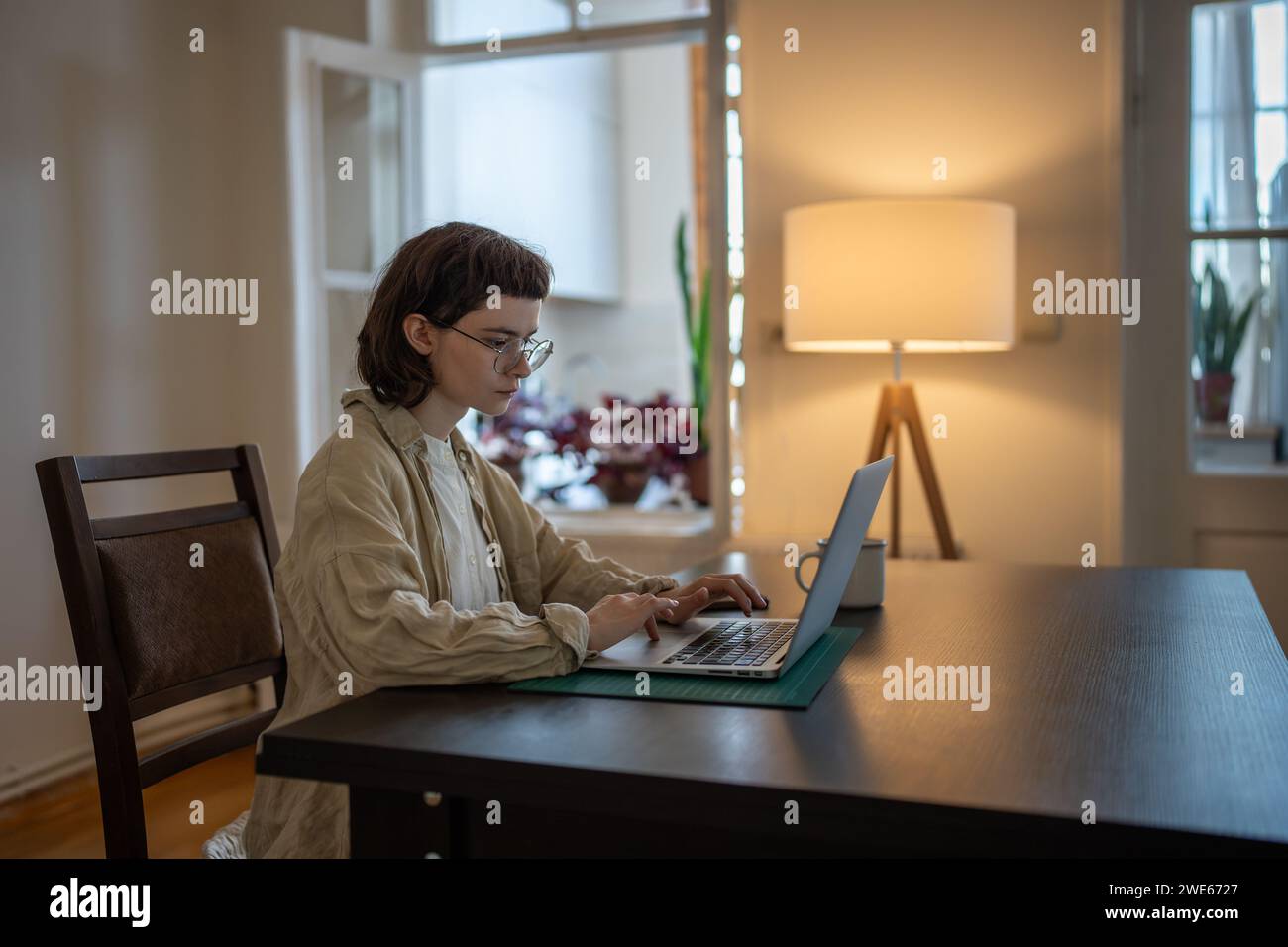 Adolescente serio che sembra freelance, studentessa, blogger, giornalista che lavora su un notebook a casa Foto Stock