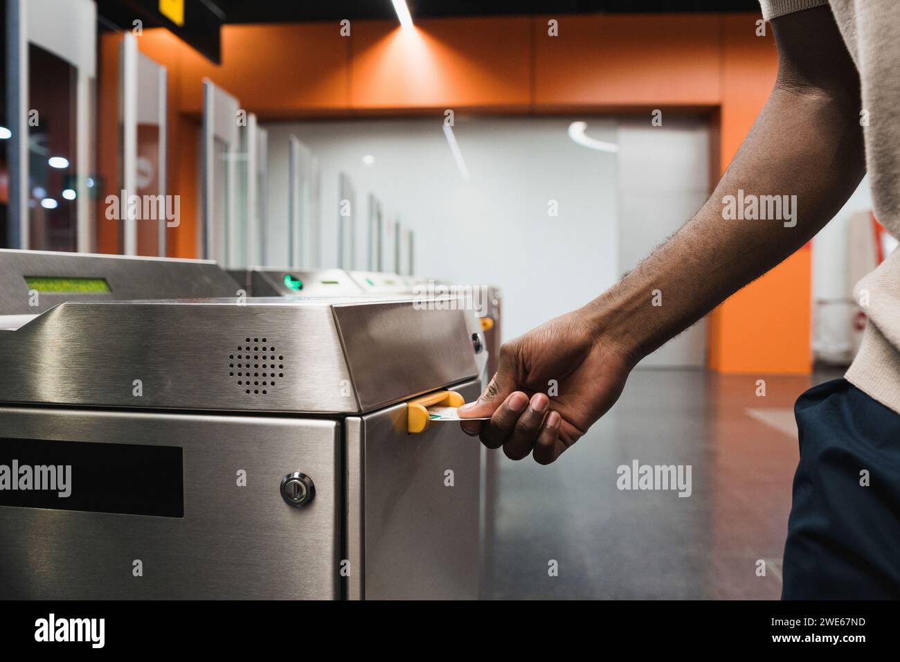 Mano dell'uomo che inserisce il biglietto della metropolitana nella barriera elettronica Foto Stock