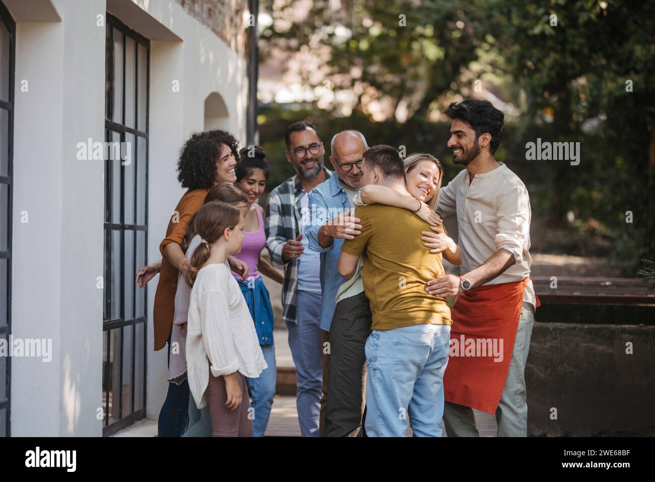 Gruppo eterogeneo di membri della comunità che abbracciano un progetto comunitario di successo Foto Stock