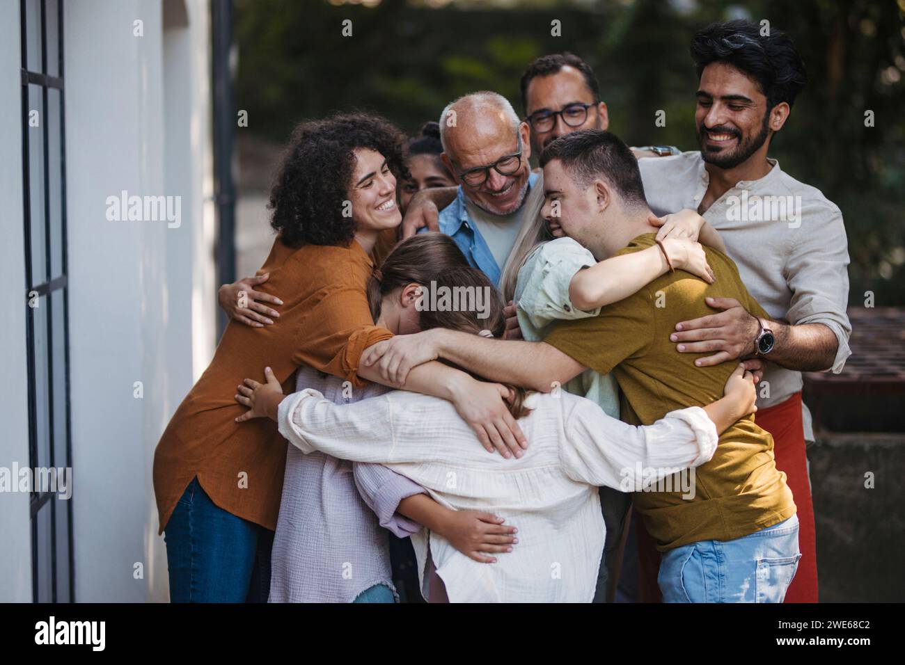 Gruppo eterogeneo di membri della comunità che abbracciano un progetto comunitario di successo Foto Stock