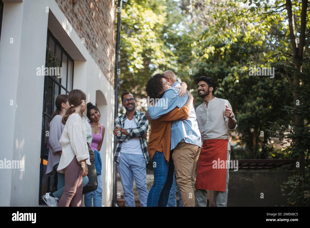 Gruppo eterogeneo di membri della comunità che abbracciano un progetto comunitario di successo Foto Stock