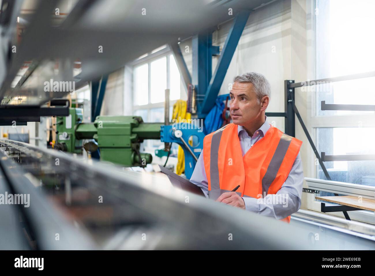 Tecnico che esamina la macchina e prepara l'elenco di controllo in fabbrica Foto Stock