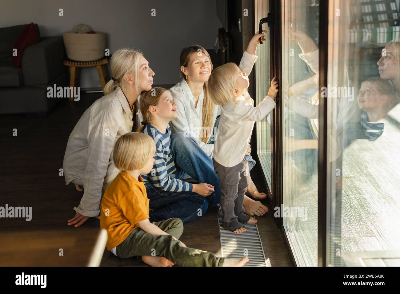 Famiglia che gioca vicino alla porta di vetro a casa Foto Stock