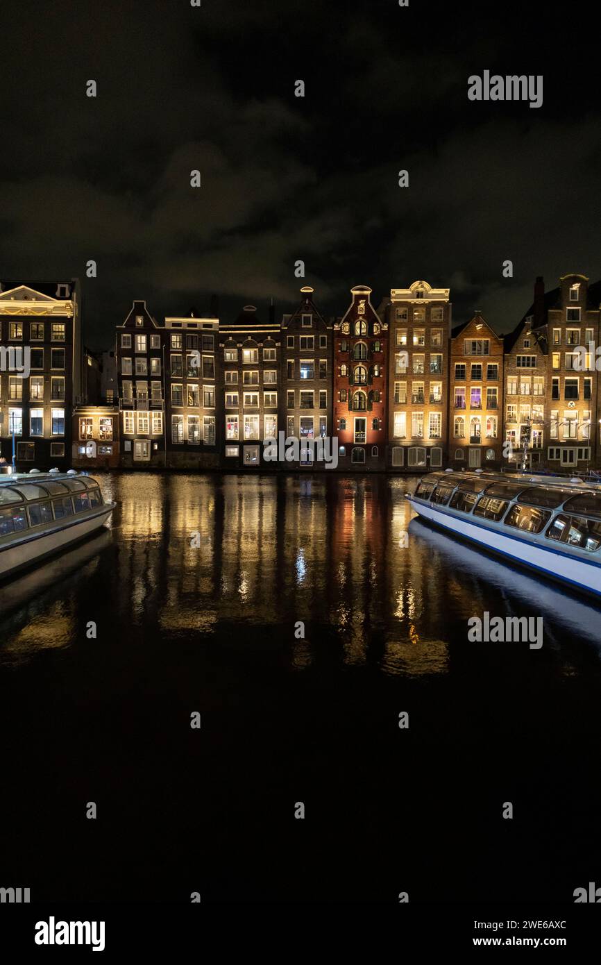 Edifici illuminati vicino al fiume di notte nella città di Amsterdam Foto Stock