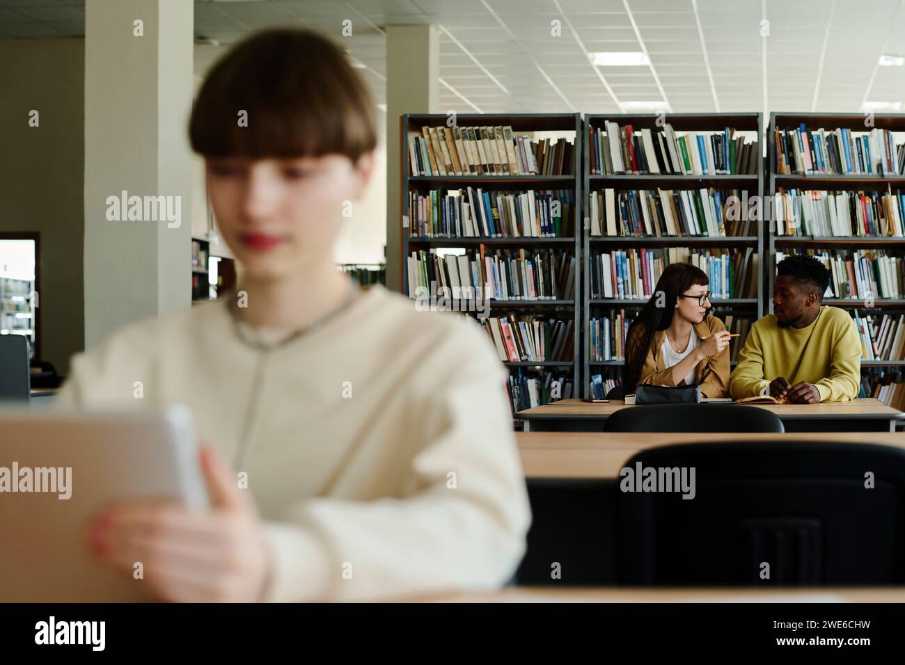 Giovani studenti che discutono in biblioteca Foto Stock
