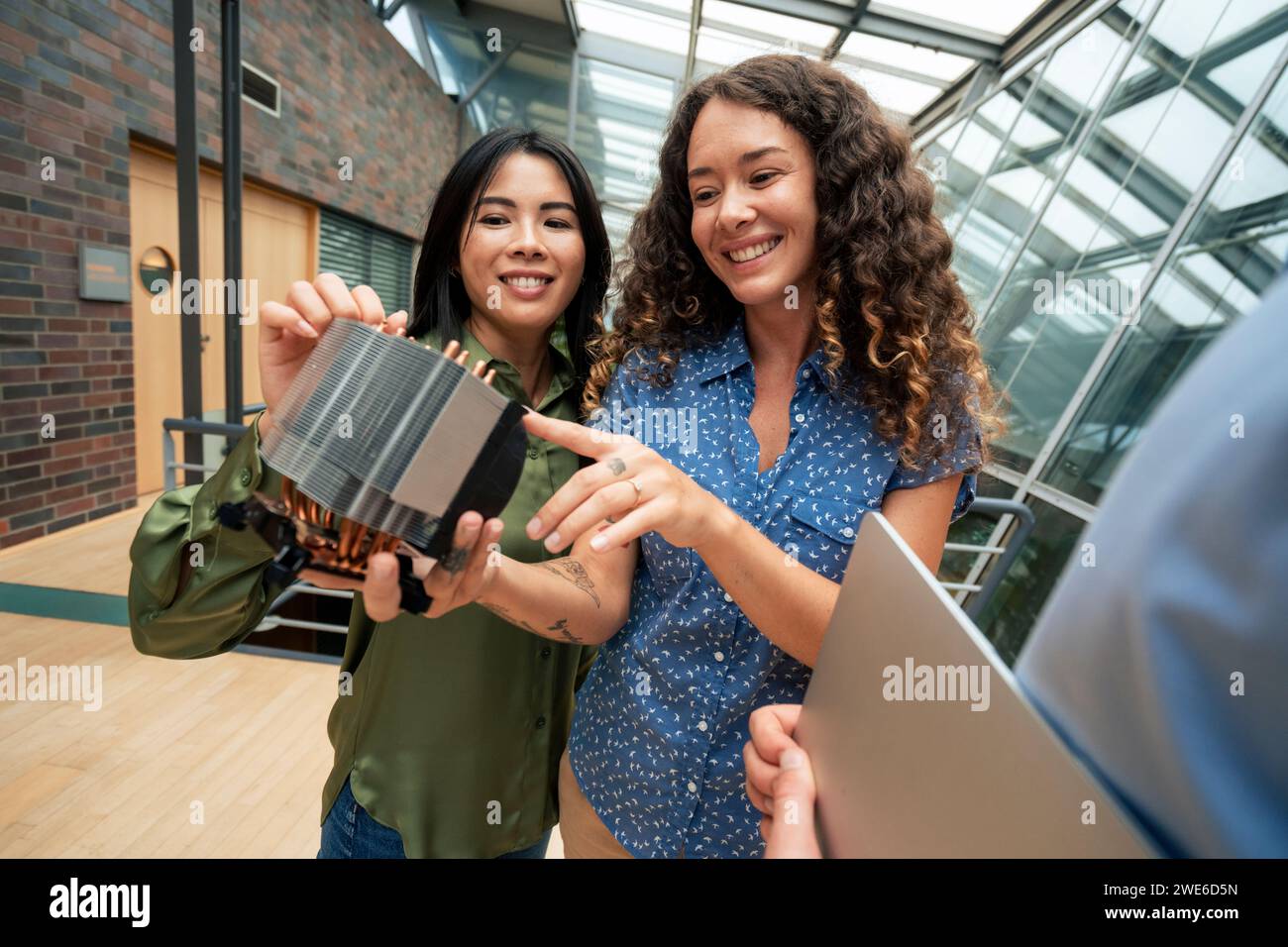 Ingegnere sorridente che discute sulla parte della macchina con un collega nel corridoio Foto Stock