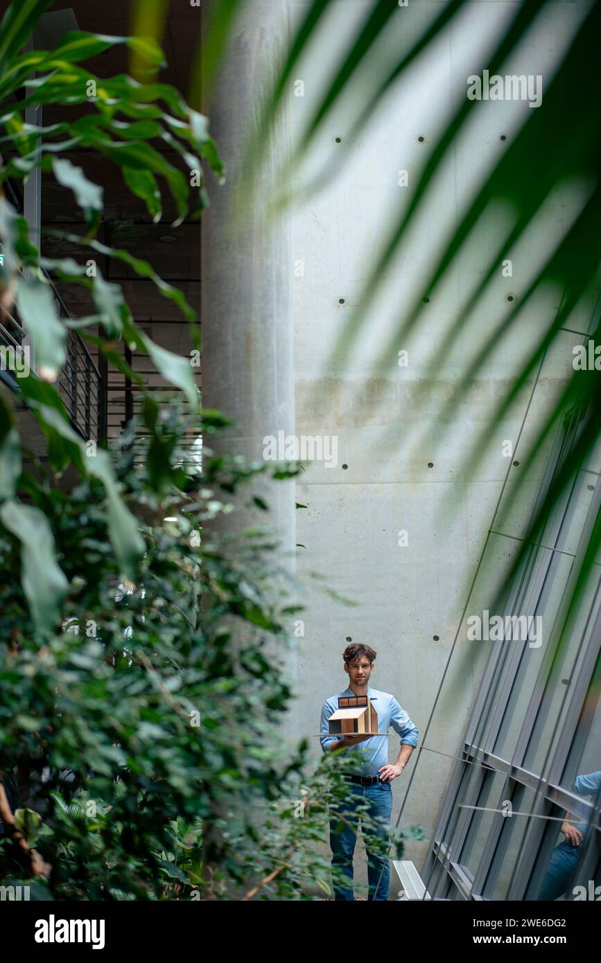 Giovane architetto con una casa modello in piedi nel corridoio Foto Stock