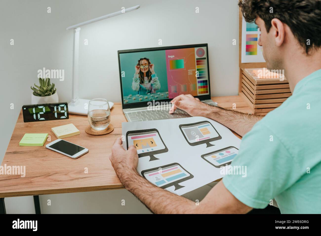Web designer che tiene un documento e lavora su un notebook in ufficio Foto Stock