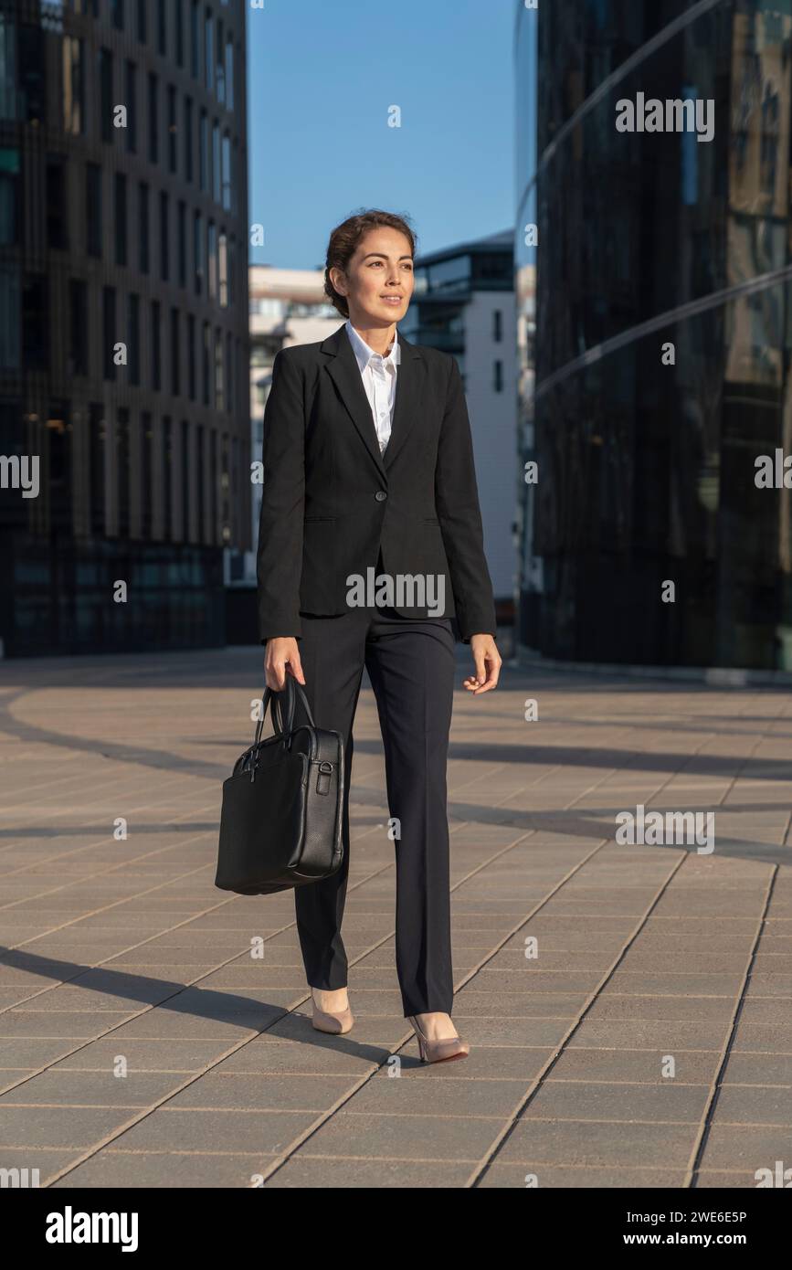 Donna d'affari che cammina con la valigetta in città Foto Stock