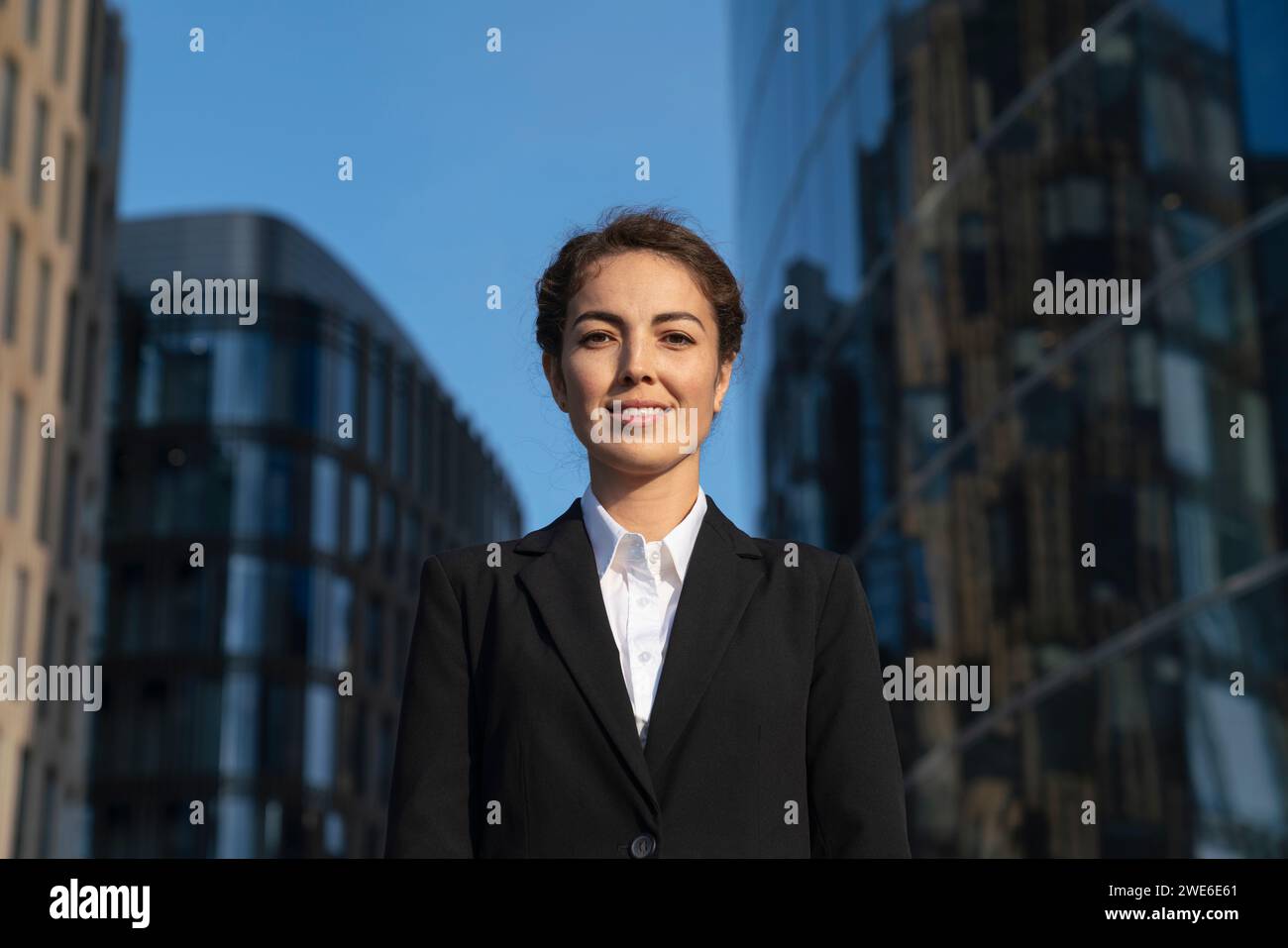 Donna d'affari sorridente vicino agli edifici della città Foto Stock