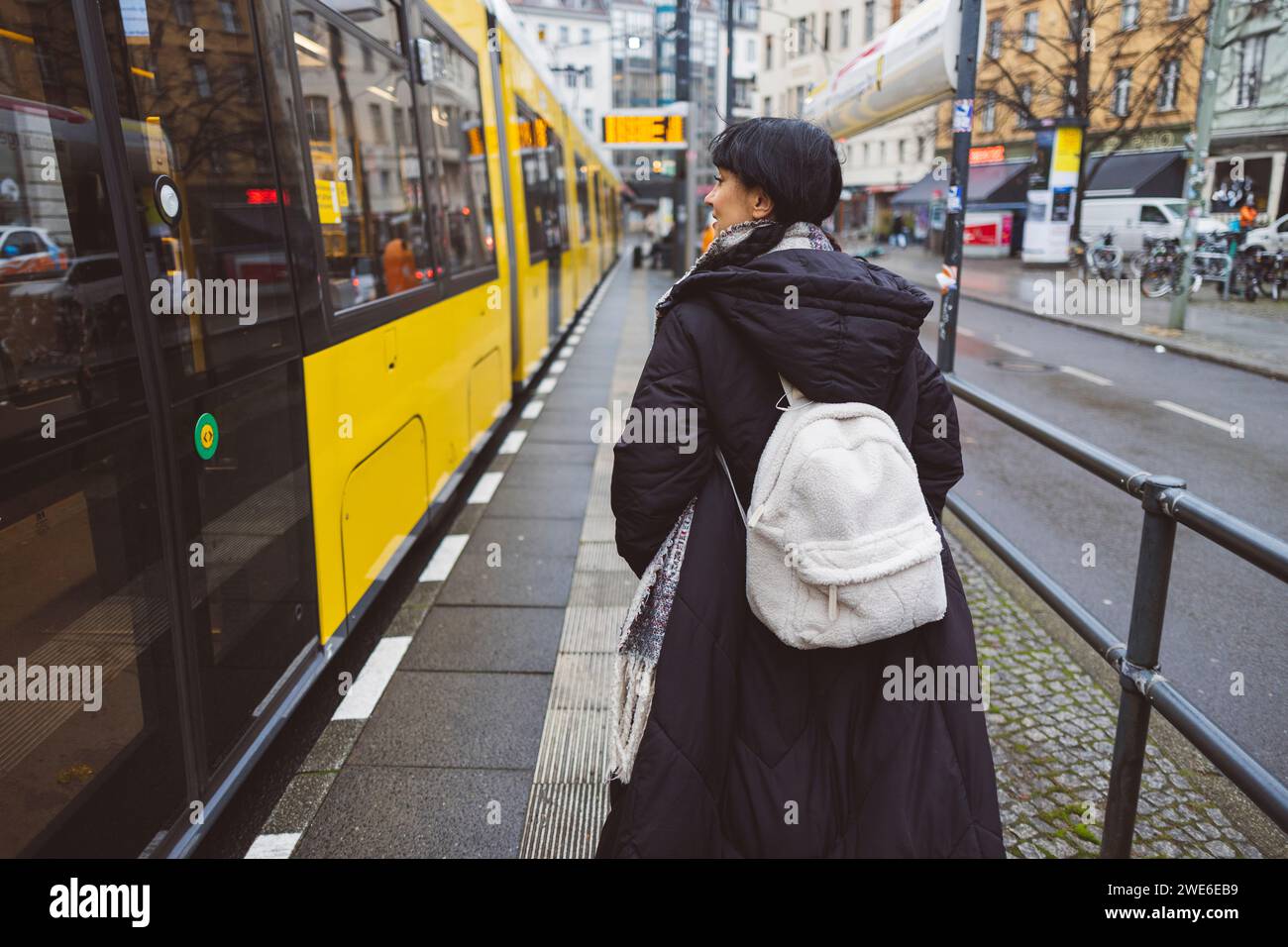 Donna con zaino che cammina vicino alla funivia alla stazione del tram Foto Stock