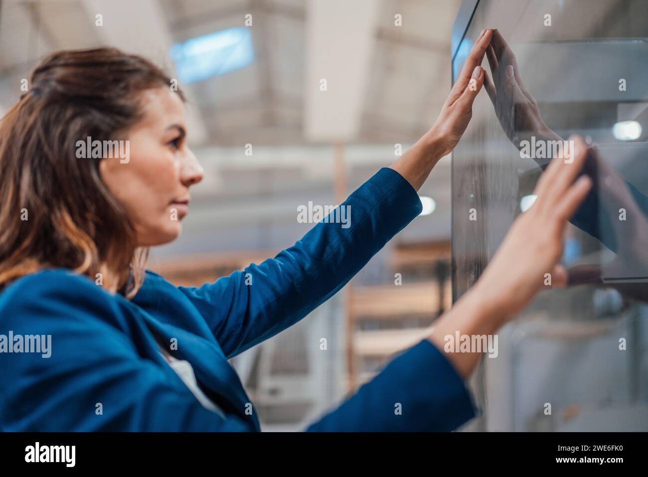 Donna d'affari che tocca lo schermo del computer nell'industria Foto Stock