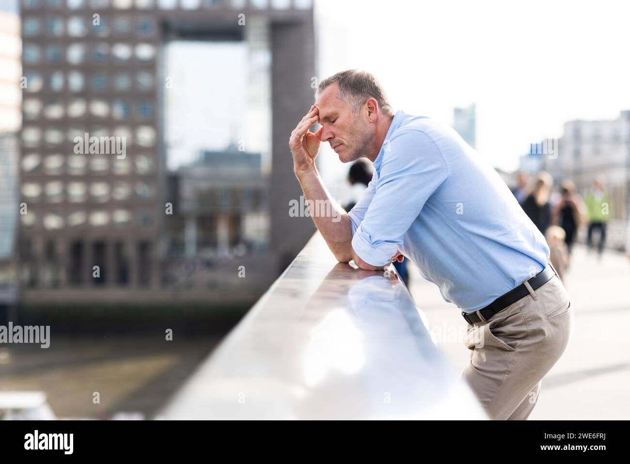 Stressato uomo d'affari che si appoggia al ponte di Londra, Regno Unito Foto Stock