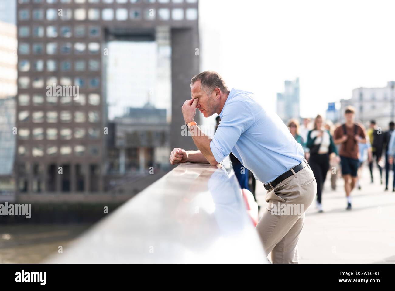 Un uomo d'affari stanco che si appoggia alle pareti e si sbatte gli occhi nella città di Londra Foto Stock