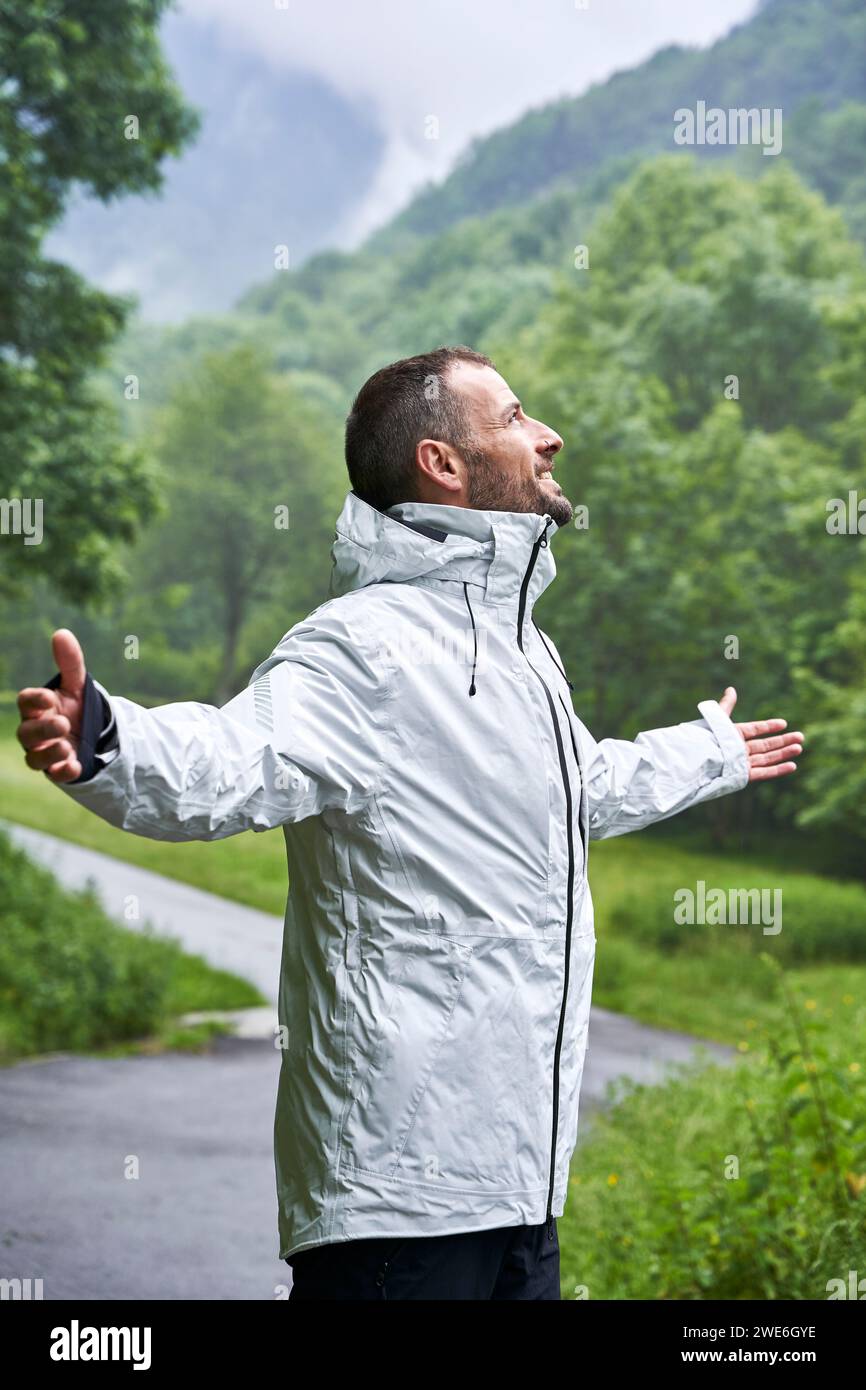 Uomo felice che indossa una giacca bianca di fronte alla montagna dei Pirenei Foto Stock