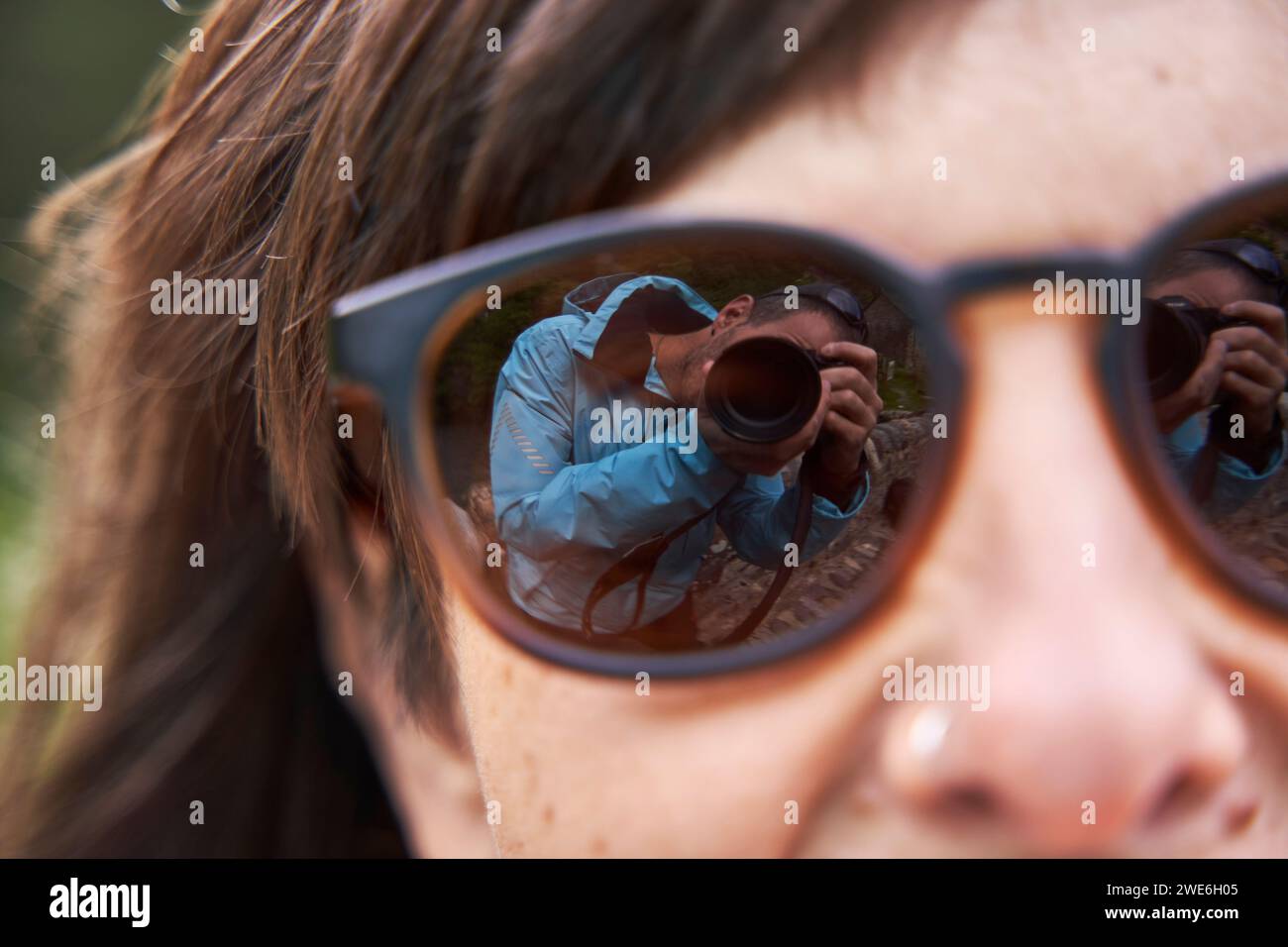 Riflesso di un uomo che fotografa attraverso la fotocamera con occhiali da sole da donna Foto Stock