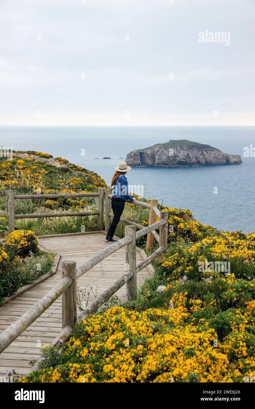 Donna addossata alle ringhiere e guardando il mare nelle Asturie, in Spagna Foto Stock