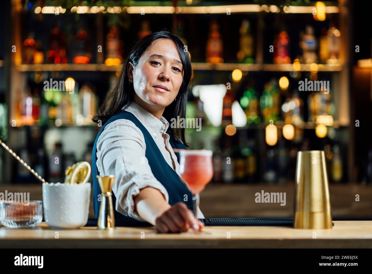 Il barman serve cocktail al banco del bar Foto Stock