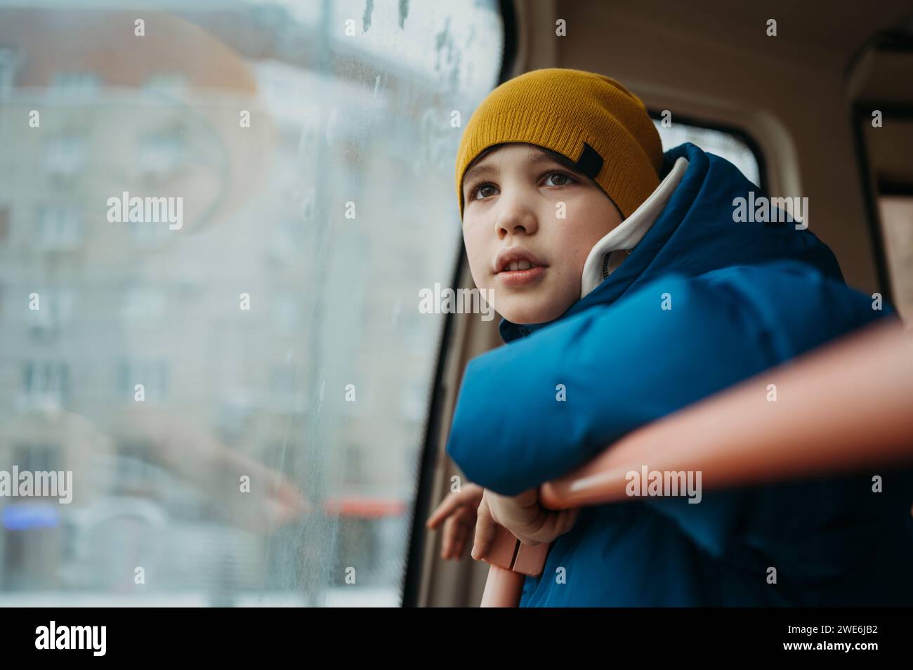 Ragazzo che viaggia in autobus e guarda dal finestrino Foto Stock