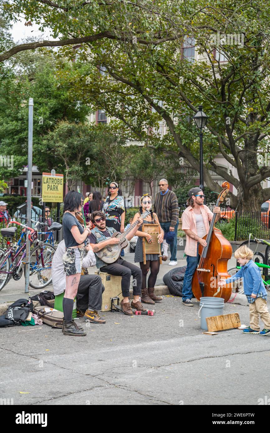 Un giovane ragazzo che mancia una band di strada acustica al Latrobe Park su Ursulines Avenue nel quartiere francese di New Orleans, Louisiana Foto Stock