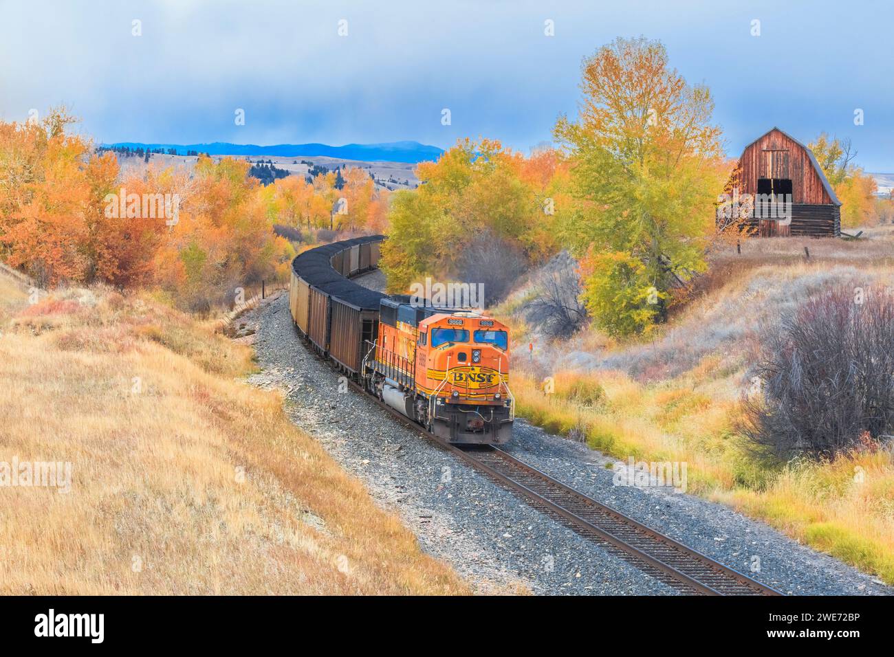 treno che passa da un vecchio fienile in autunno a jens, montana Foto Stock