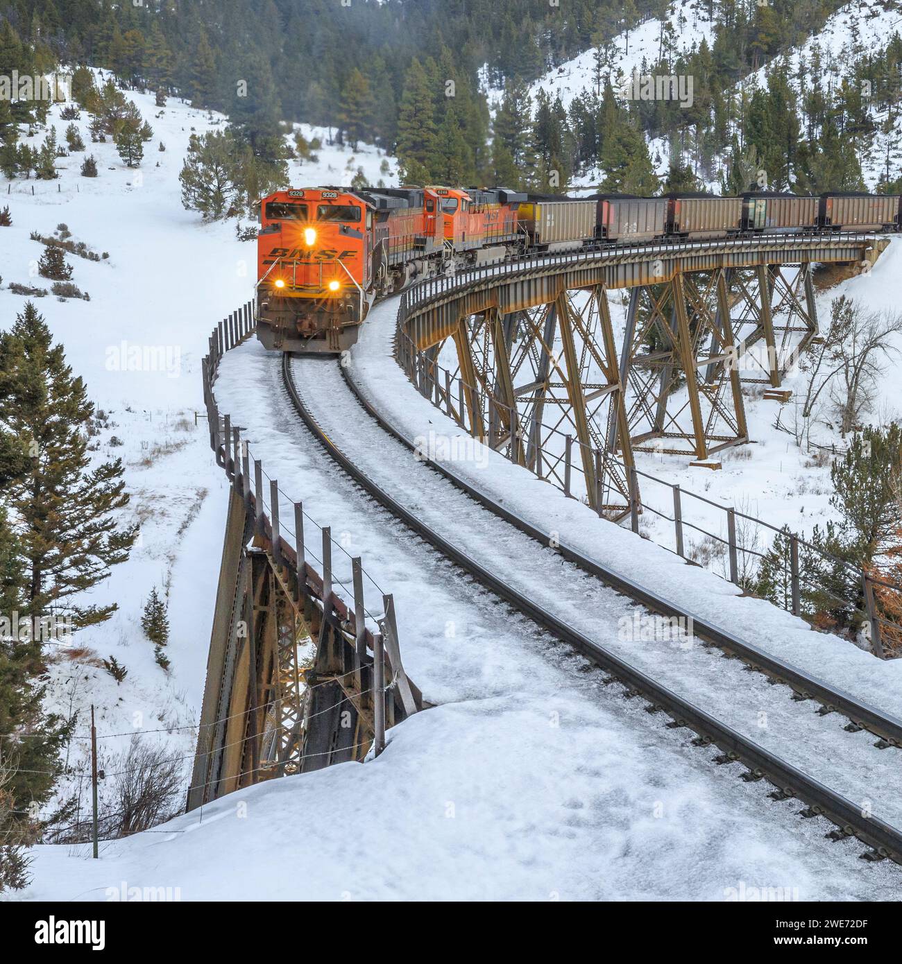 il treno che trasporta le carrozze a carbone verso mullan passa sopra un cavalletto in inverno vicino ad austin, montana Foto Stock